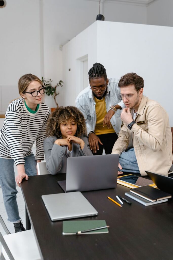 pexels-photo-7550396-7550396 A diverse team of adults collaborating in a modern office setting with laptops and notebooks.